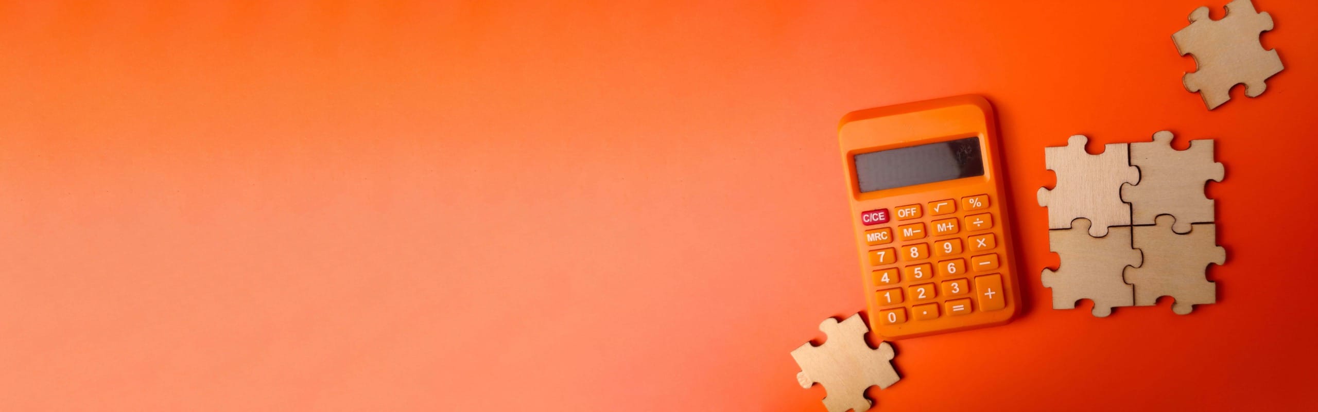 calculette et pièce de puzzle en bois sur fond rouge